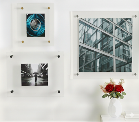 Wall with sandwich framed pictures and a vase of flowers on a white surface